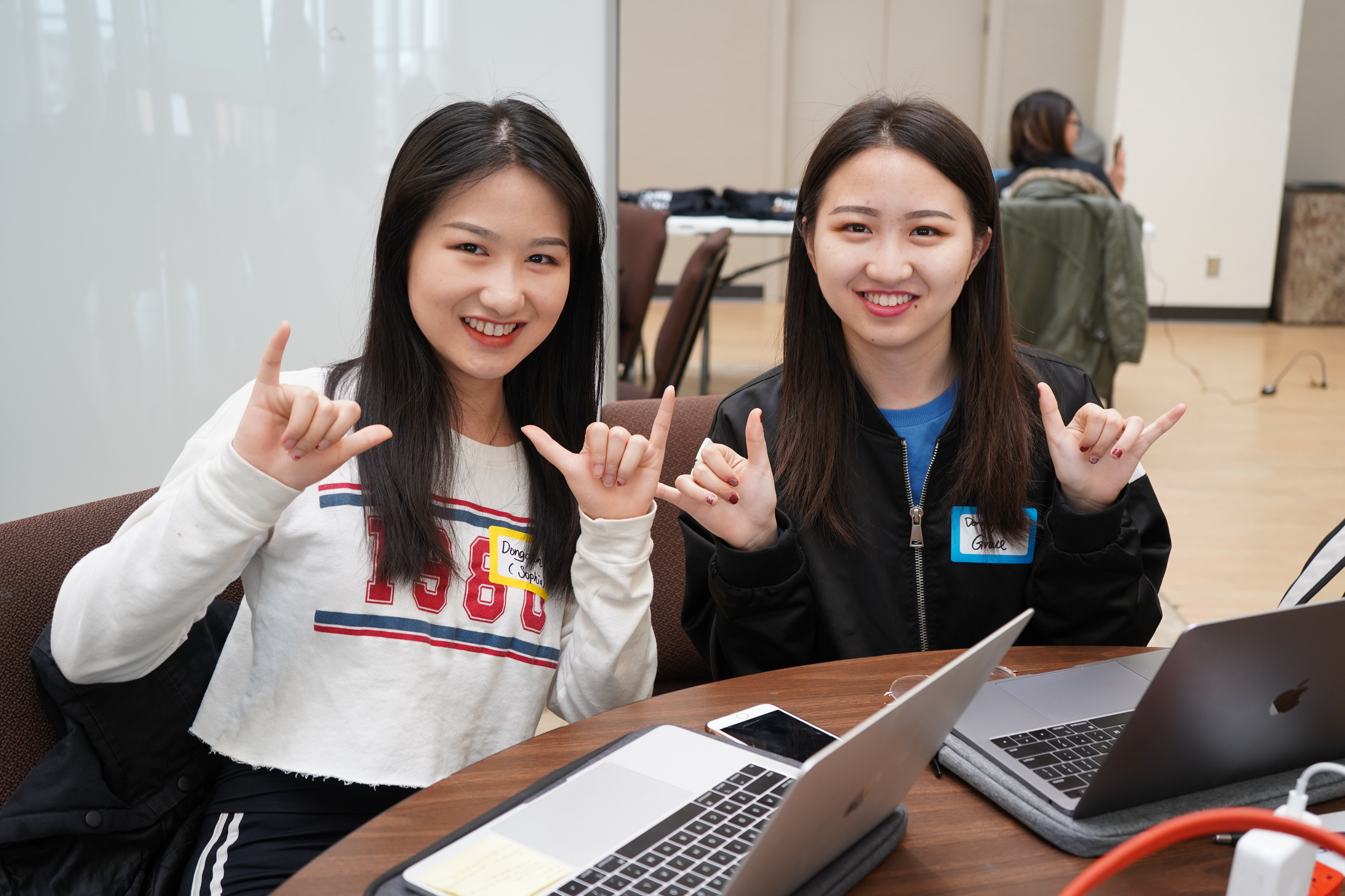 two young women giving the mav up hand gesture