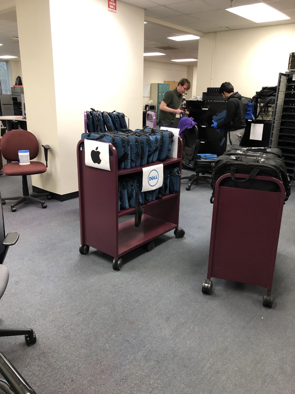 two staff members prepare carts of laptops for check out