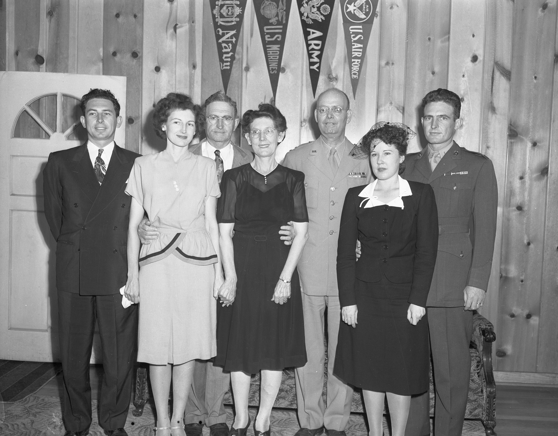 Memorial service for Lieutenant Colonel William J. Boydstun, May 6, 1945. Left to Right: Ira S. Boydstun, Mrs. Iva Guthrie, J. J. Boydstun and Mrs. Boydstun, Major General Gilbert R. Cook, Mrs. Tylene Boydstun, William Boydstun's widow, and Lieutenant Robert Boydstun of the Marines who is at home on leave. Ira and J.J. are in suits, the women are in 1940's style dresses, Tylene Boydstun also wears a small veil on her head. General Cook and Robert are in uniform. 