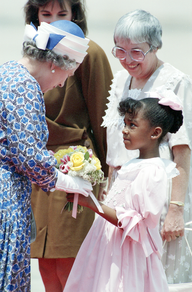Young girl gifting a bouquet of flowers to Queen Elizabeth II.