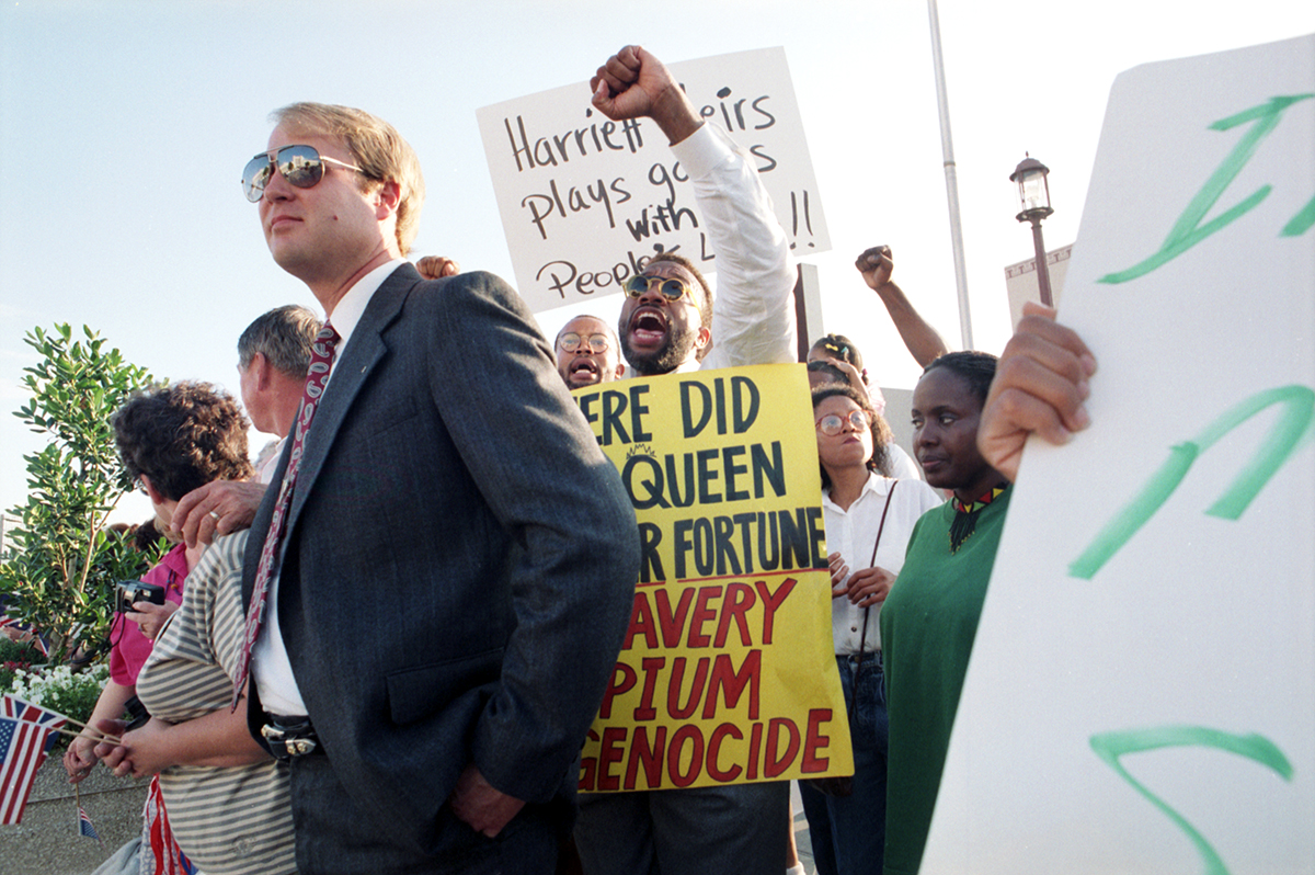 John Wiley Price, with his fist in the air, holding a sign while protesting.