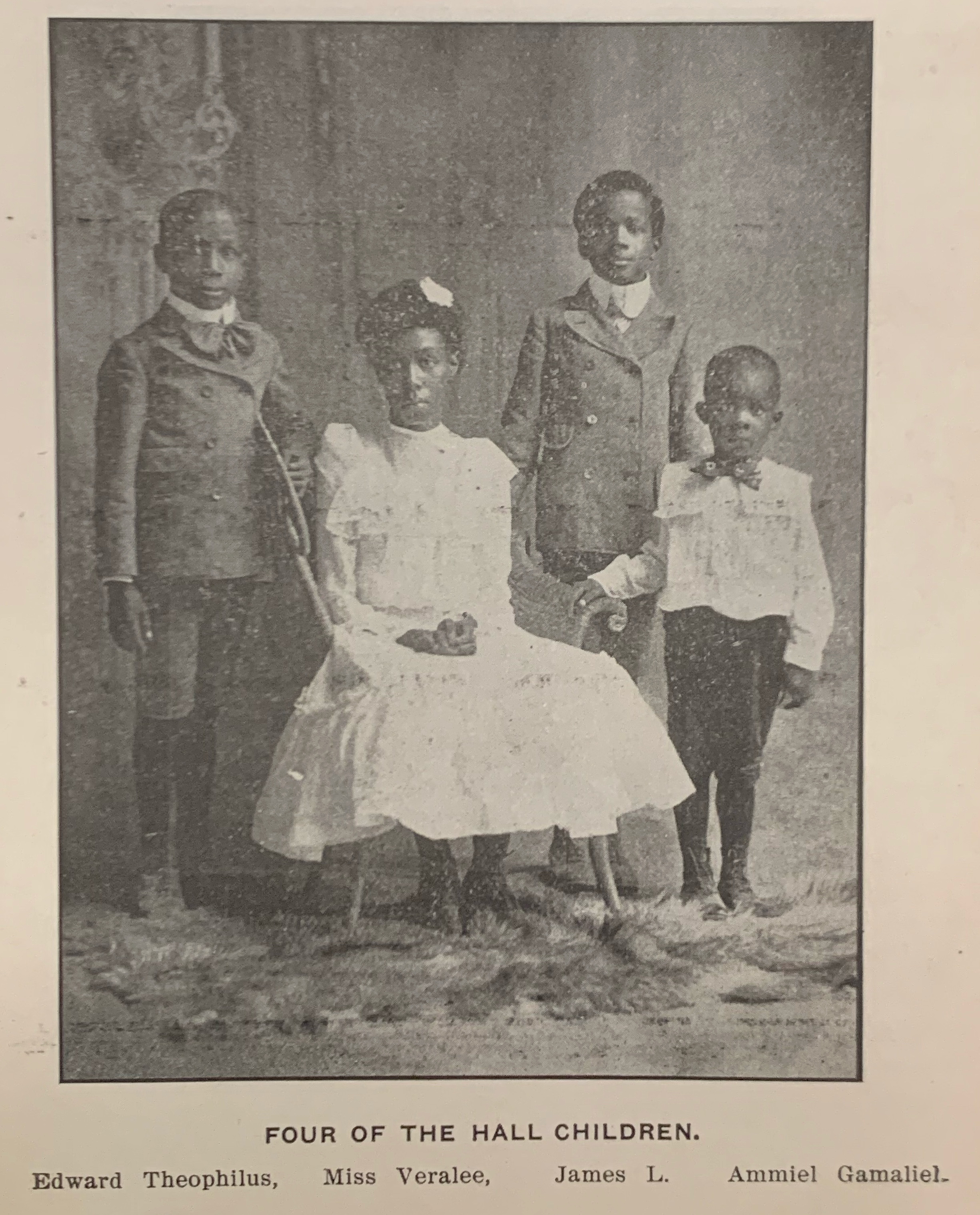 Four African-American children, three boys and one seated girl, in 1900's style clothing. Text reads: Four of the Hall children. Edward Theophilus, Miss Veralee, James L., Ammiel Gamaliel.