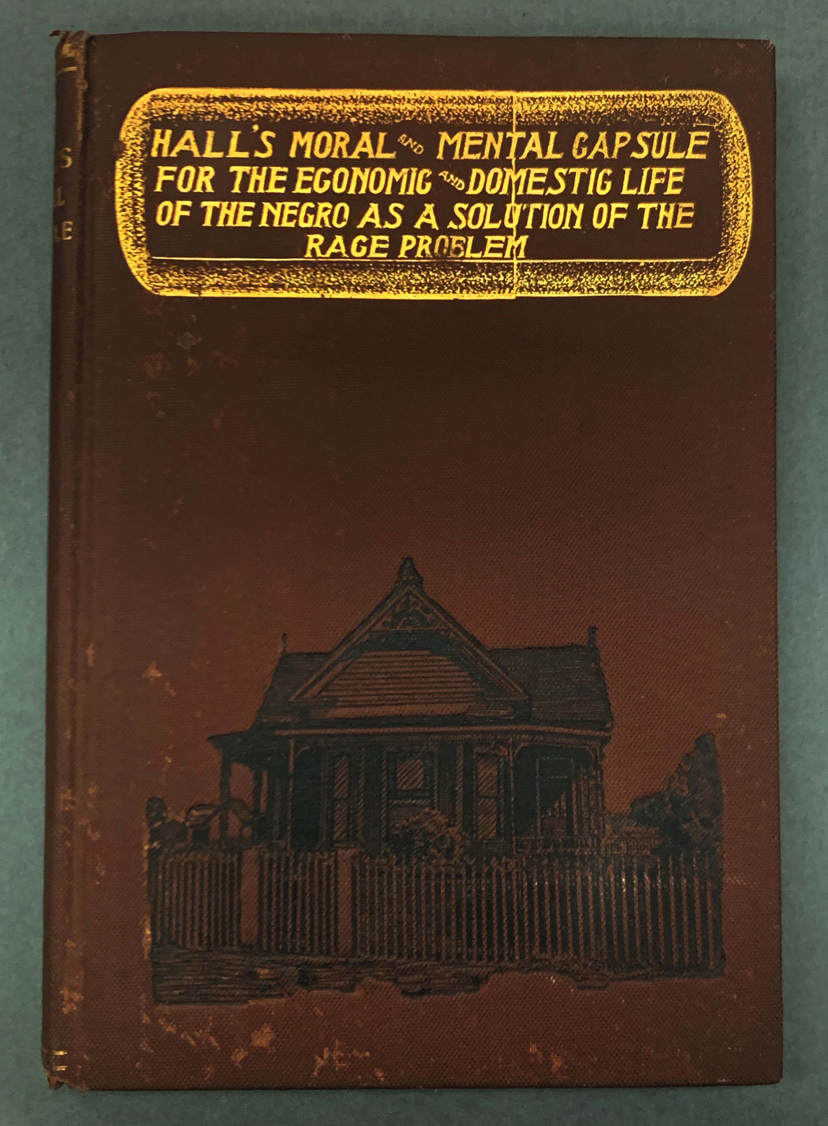 Book with image of a single story Queen Anne's style house. Gold title reads: Hall's Moral and Mental Capsule for the Economic and Domestic Life of the Negro as a Solution of the Race Problem"