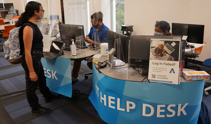 student requesting help from workers behind the IT Help Desk