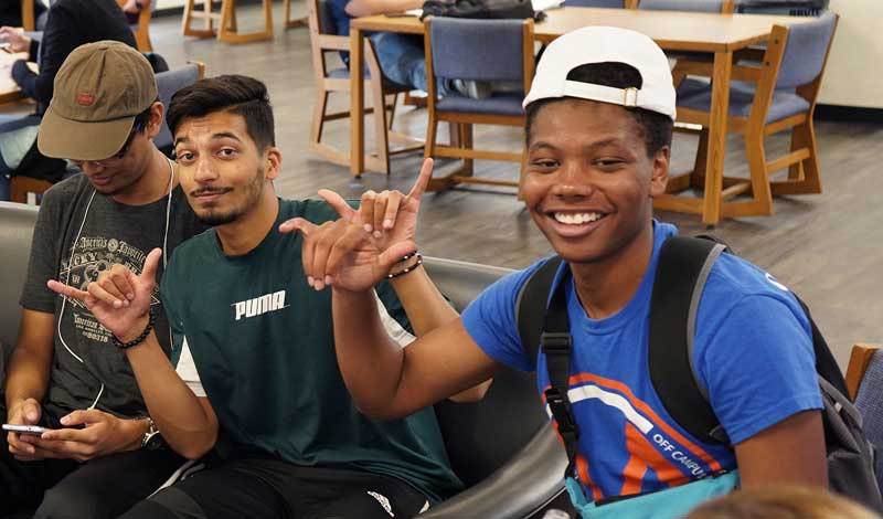 Students smiling and showing the Maverick hand signal