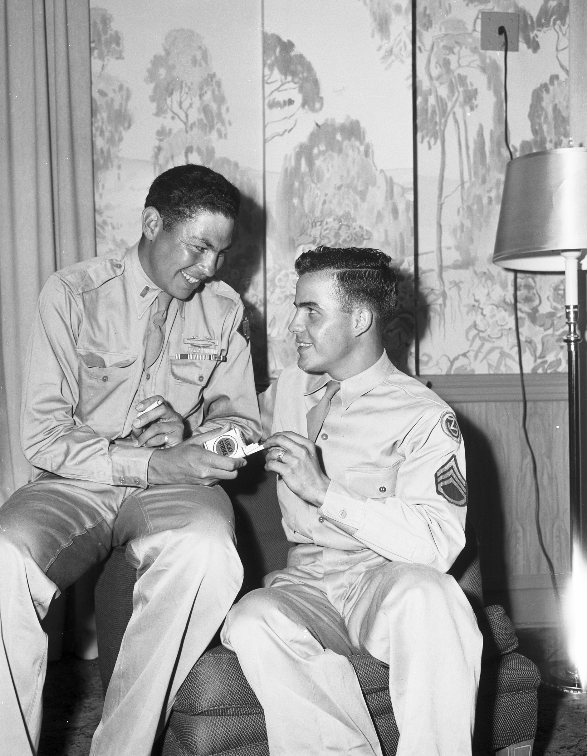 Lieutenant Ernest Childers and Sergeant Bill Goforth. Two Indigenous men in World War II army uniforms sitting together and sharing cigarettes. 