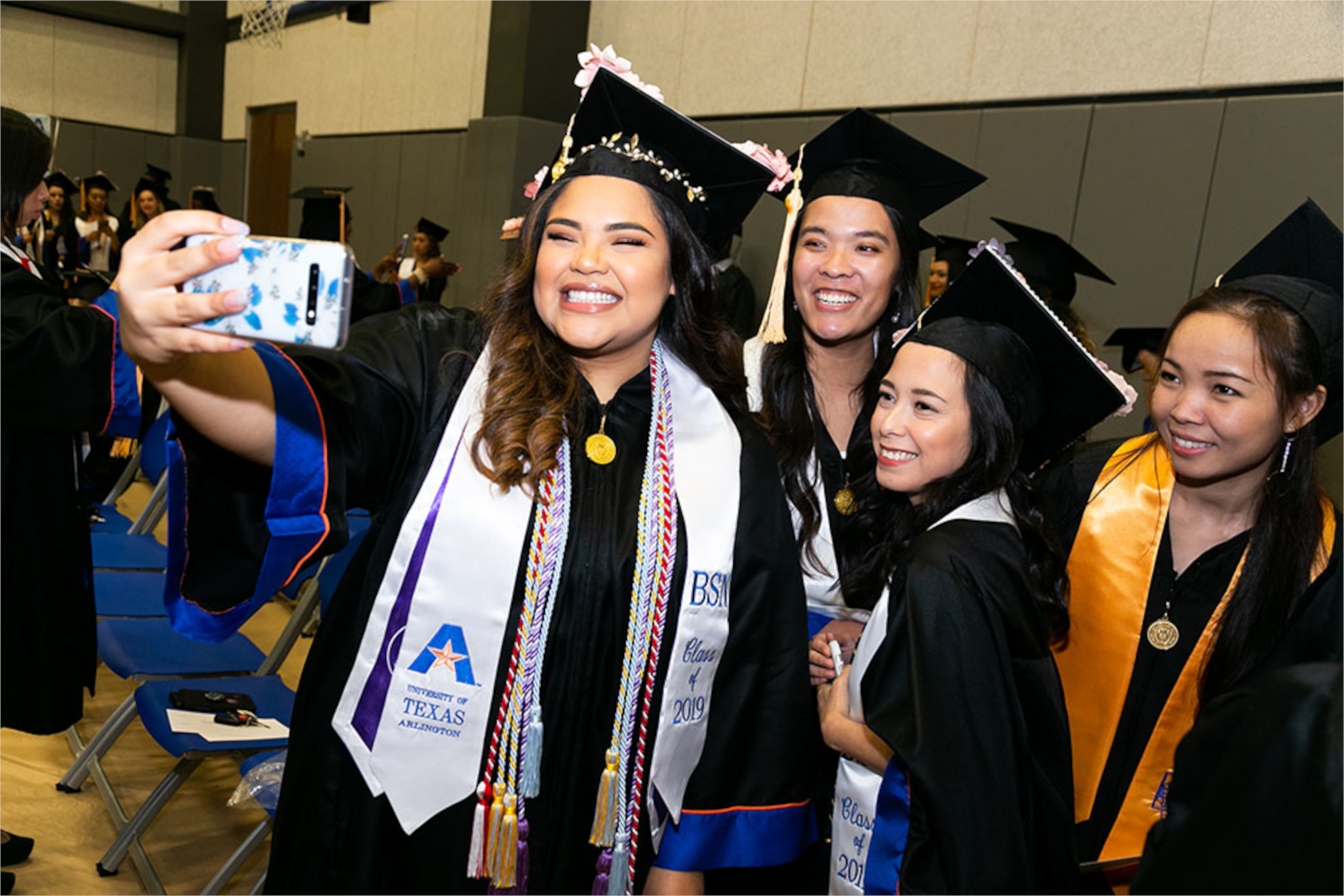 Three nurses in cap and gown taking a selfie.