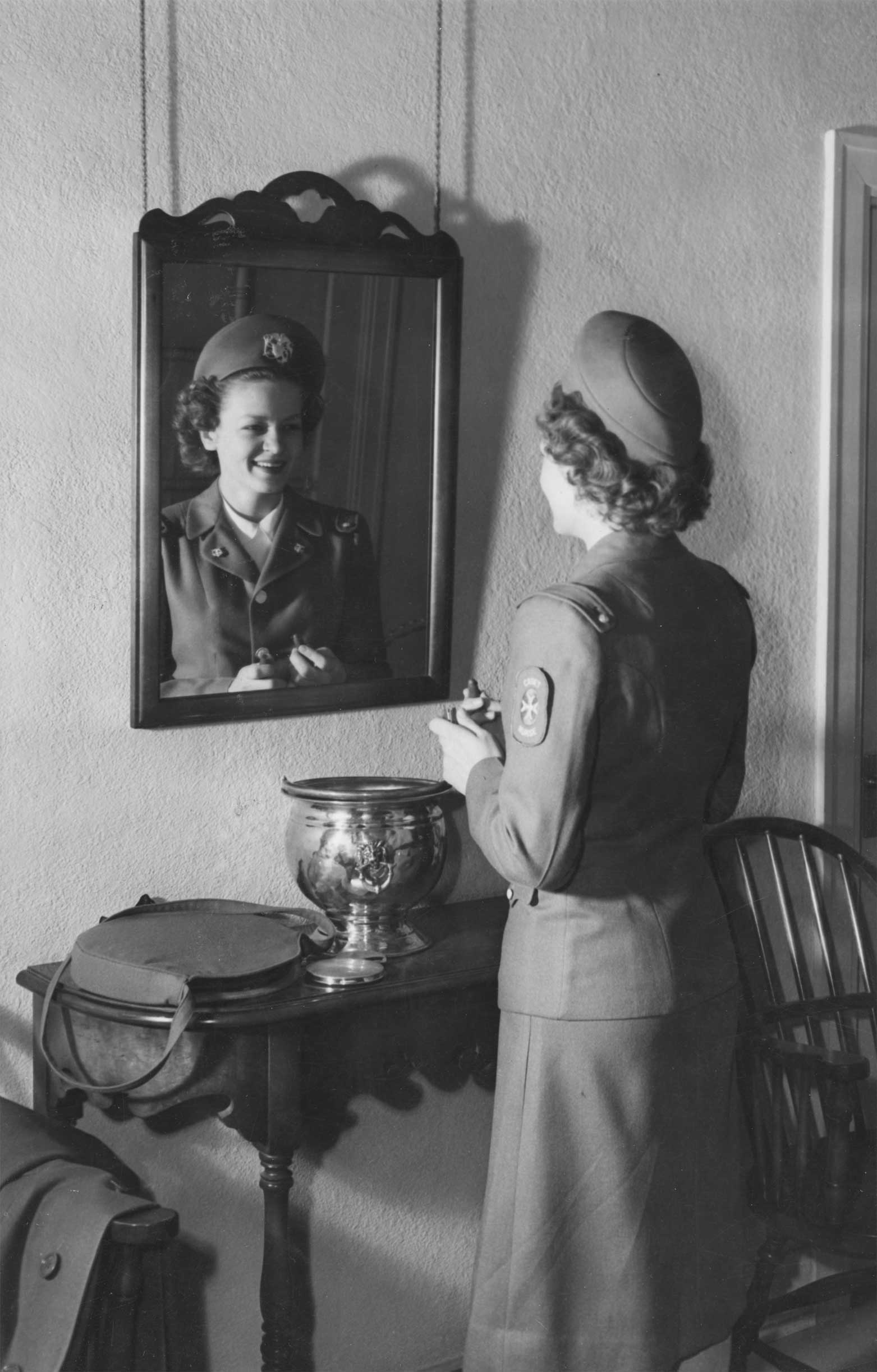 Nurse in a military uniform looking at herself in a mirror.