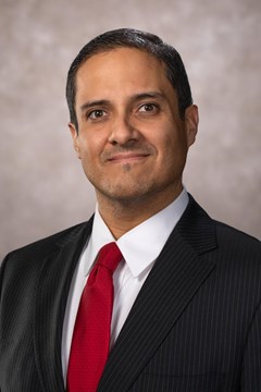 A headshot of Dr. Xavier Medina Vidal in a black suit and red tie.