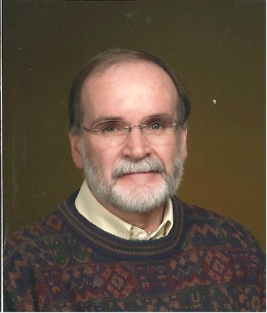 Head shot of man wearing glasses and wearing a sweater. 
