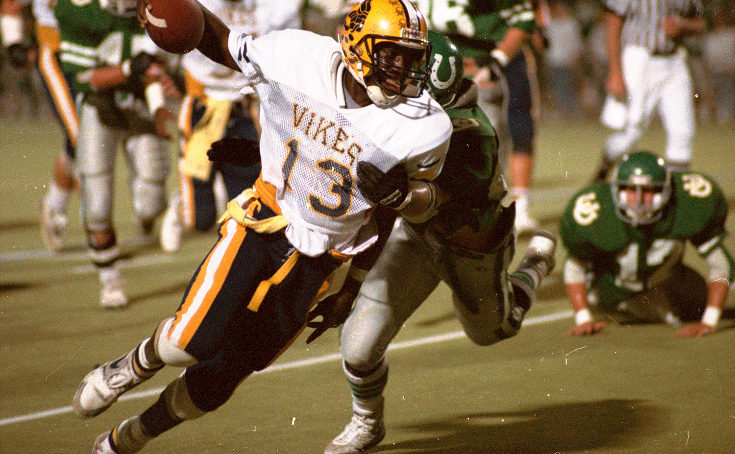 A young football player runs with the ball with an opposing player hot on his trail.