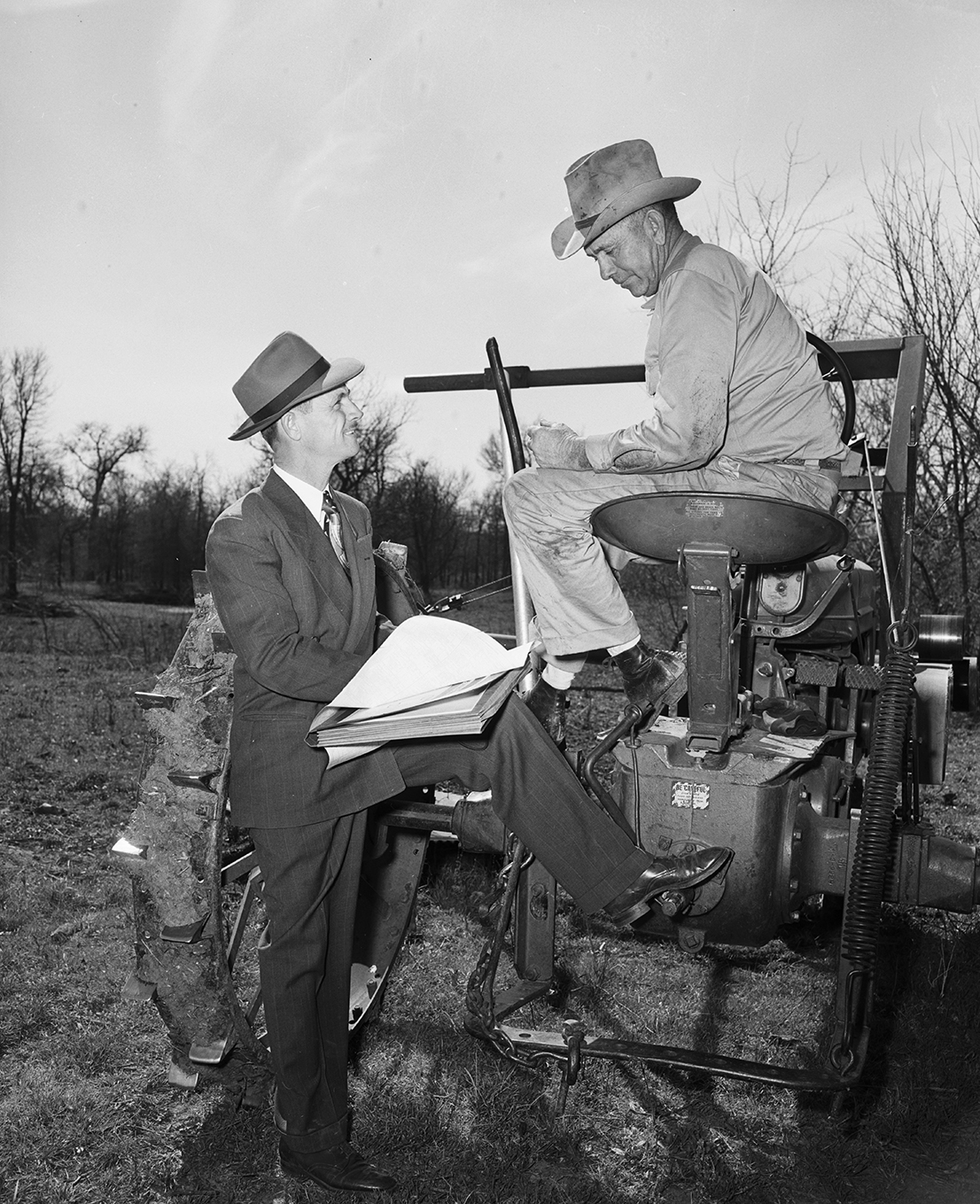 Willard Kemplin, who farms in Cooke County, at Valley View, pulled up on his tractor to answer census questions of Tim Osborn, Gainesville census crew leader. March 1950.