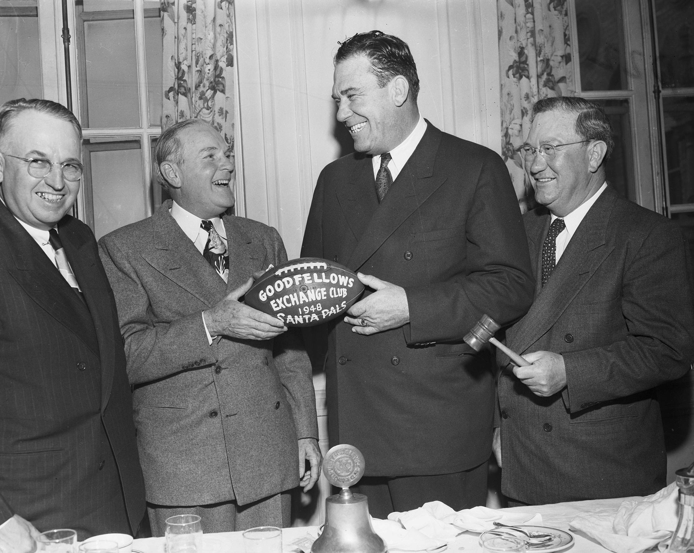 Group of men at a Goodfellows fundraising event, holding an autographed TCU football.