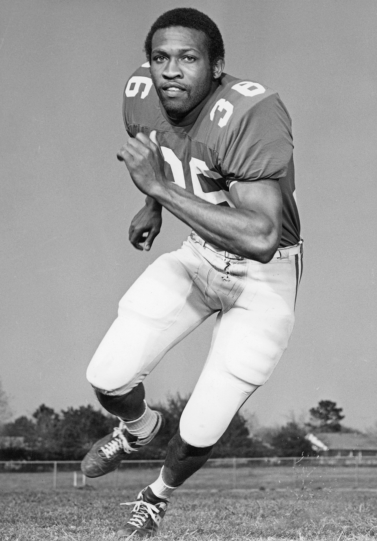 Black and white photo of a posed football player in football jersey.
