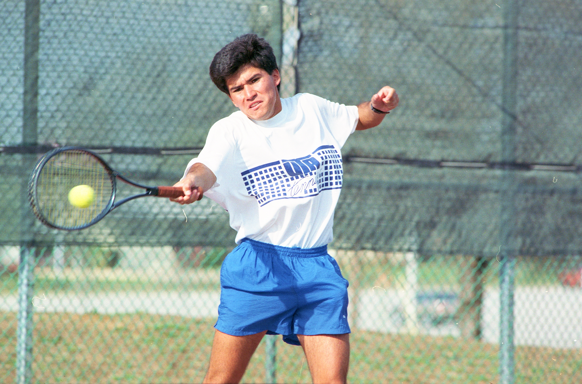 Color photo of a tennis player hitting the tennis ball with a racquet during a tennis match.