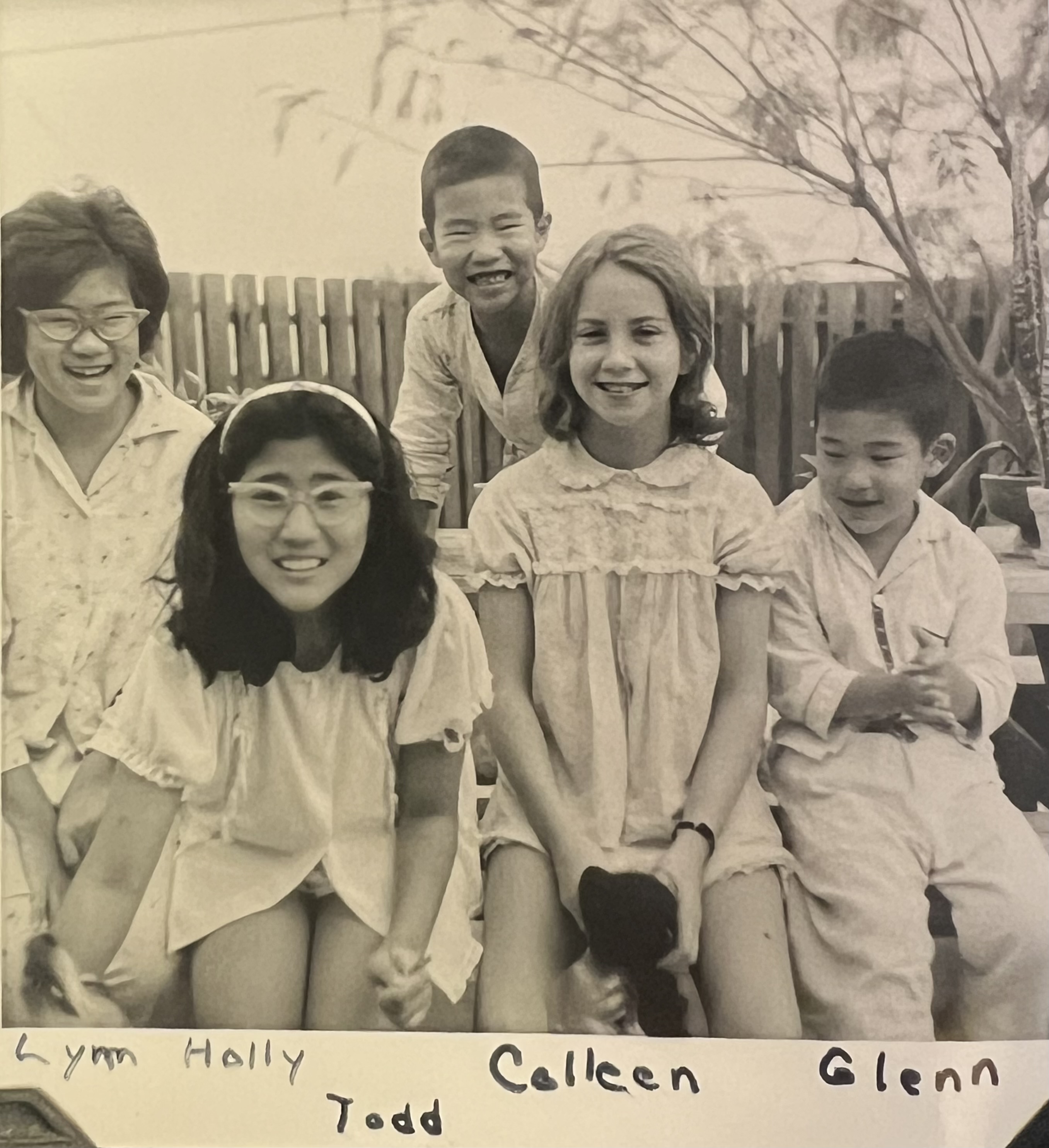 A group of smiling children sitting at an outdoor table, wearing 1960s pajamas. The text reads 'Lynn, Holly, Todd, Colleen, Glenn'.