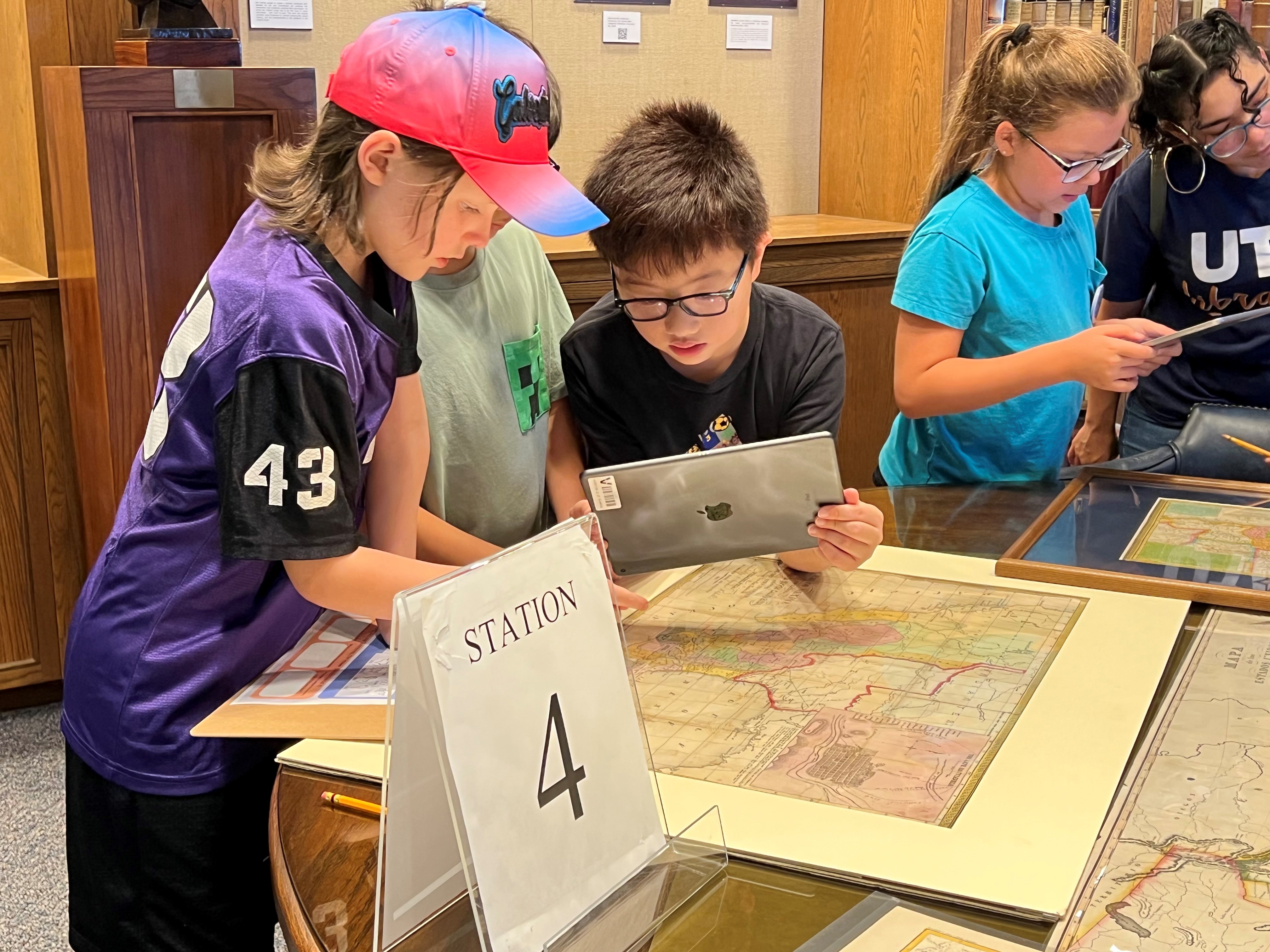 Young students studying maps and other items in Special Collections.