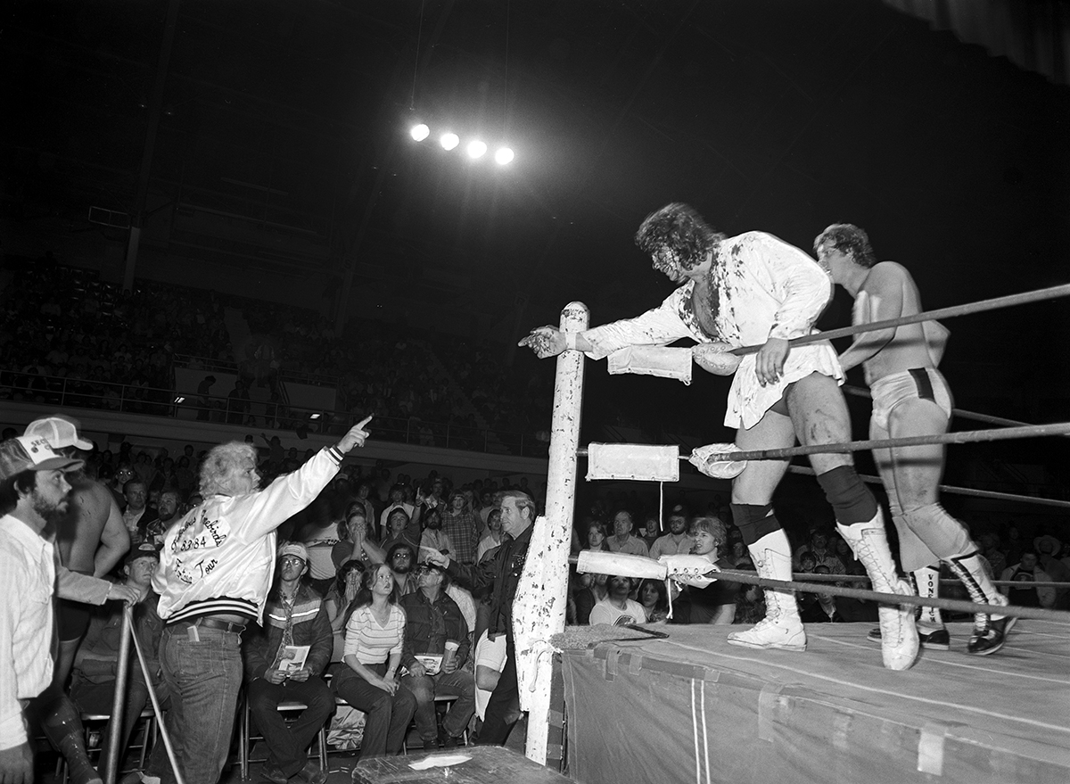 Wrestling at Will Rogers Coliseum, Fort Worth, Texas ca. 1983-84; Kerry Von Erich [Kerry Adkisson] is seen injured in the ring with a bloodied face, pointing at Buddy Roberts wearing a "Fabulous Freebirds, 1983-1984" letterman jacket. David Von Erich is seen just behind Kerry.