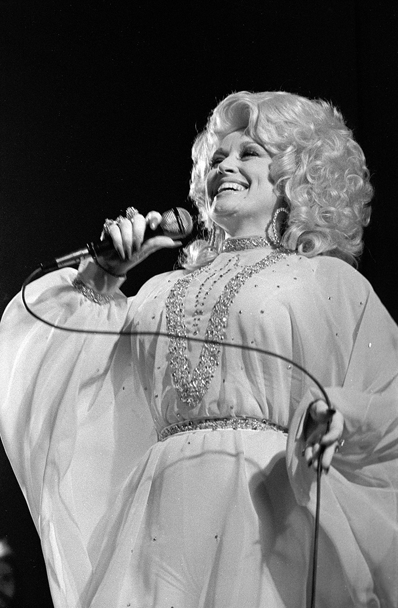 Dolly Parton with a microphone while performing in concert.