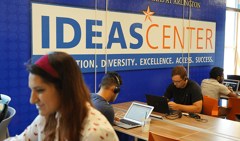 students studying beneath IDEAS Center sign