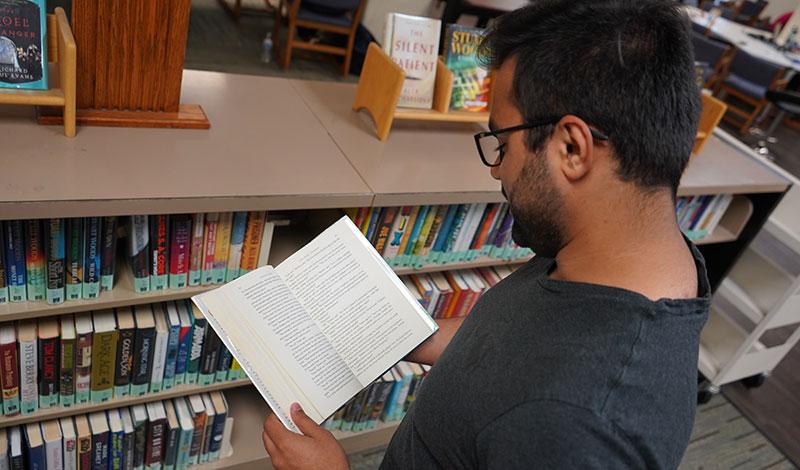 student looking at a book in the popular reading collection