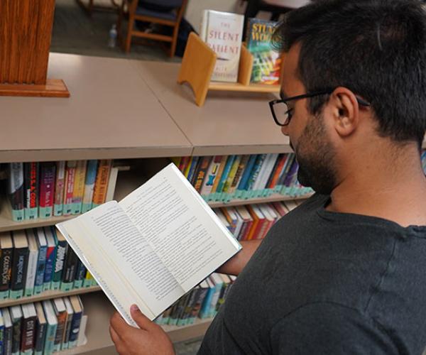 student looking at a book in the popular reading collection