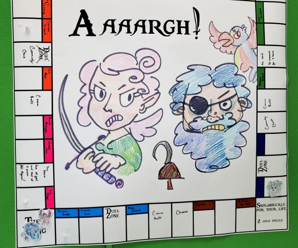 A pirate themed board game using a blank monopoly board. A hand drawing of a fairy holding a dagger and a pirate with eye-patch and hook take up the center of the board.