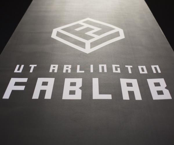 U T arlington FabLab logo sign from a downward angle pointing up