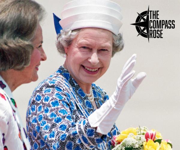 Queen Elizabeth, wearing a hat, and waved with her right hand, which is covered in a white glove, while holding a bouquet of flowers in her left hand.