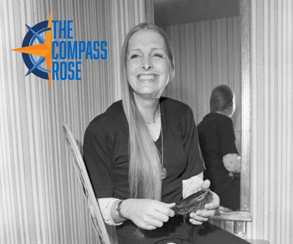 Woman smiling and holding a hear brush with the Compass Rose logo in the top left corner. 