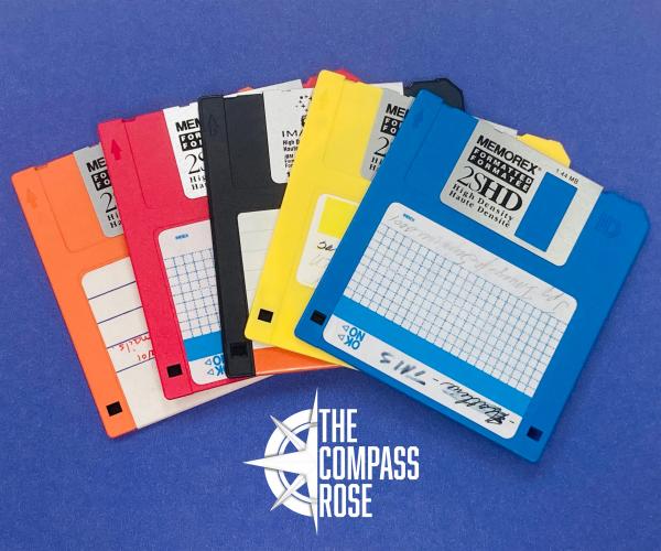 Multi-colored floppy disks displayed in a row with the Compass Rose logo below them. 