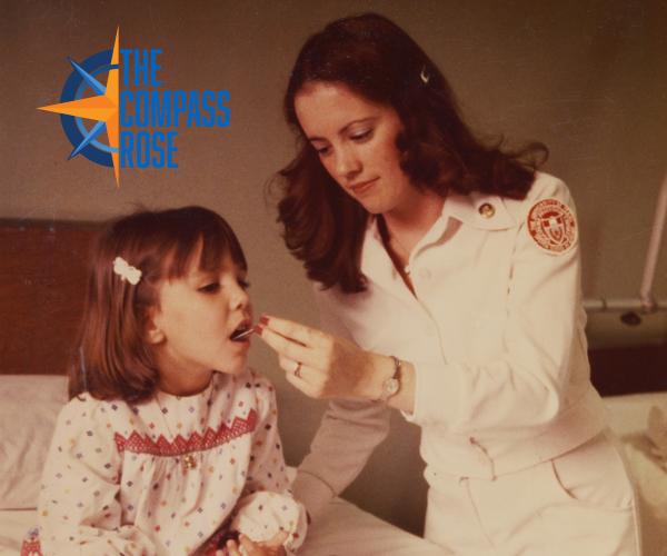 Nurse taking the temperature of a girl sitting on a hospital bed. In the top left corner, "The Compass Rose" logo.
